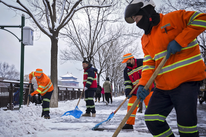 Trabajadores municipales despejan la nieve en una calle cerca de la Ciudad Prohibida tras una nevada en Beijing, el lunes 11 de diciembre de 2023.