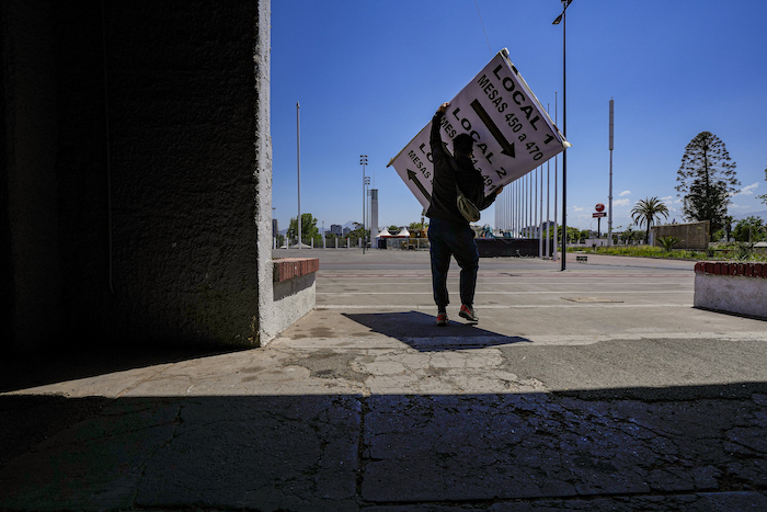 Un empleado electoral carga un cartel informativo en un local de votación montado en el Estadio Nacional, un día antes de un plebiscito constitucional, en Santiago, Chile, el sábado 16 de diciembre de 2023.