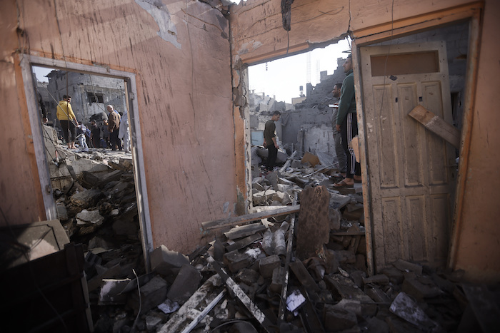 Un grupo de palestinos observan la destrucción causada por bombardeos israelíes en el campamento de refugiados de Jan Yunis, en la Franja de Gaza, el viernes 1 de diciembre de 2023.