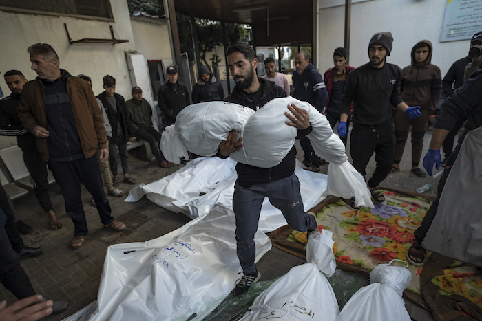 Un hombre palestino carga con el cadáver de un familiar muerto en un bombardeo israelí sobre la Franja de Gaza, en el exterior de una morgue en Rafah, en el sur del enclave, el 29 de diciembre de 2023.