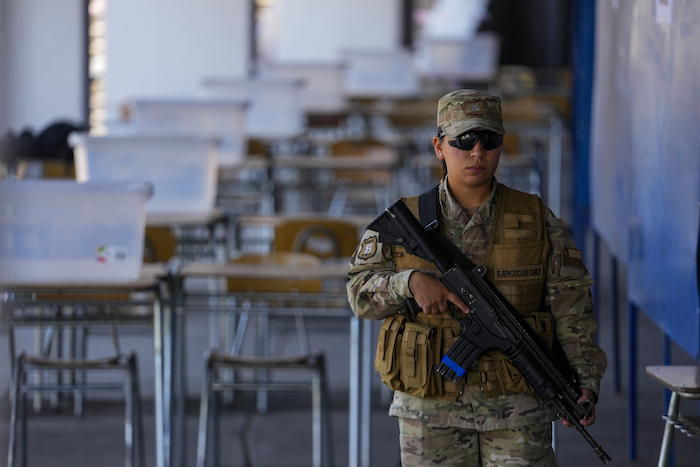 Una mujer soldado monta guardia en un local de votación montado en el Estadio Nacional, un día antes de un plebiscito constitucional, en Santiago, Chile, el sábado 16 de diciembre de 2023.