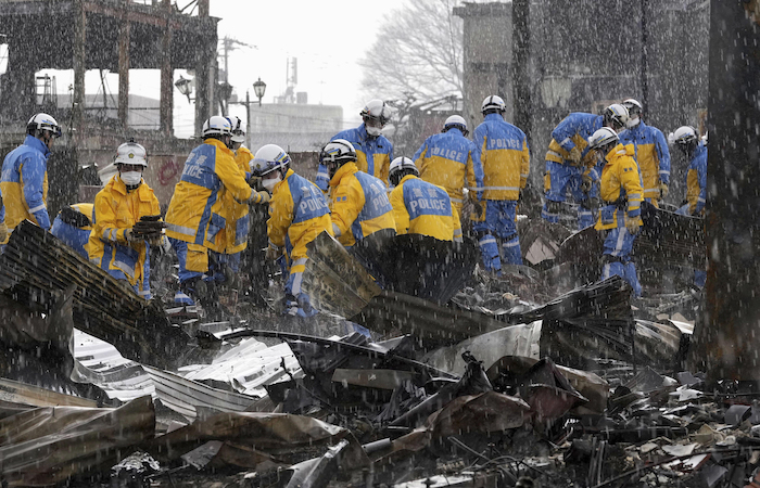 Cae la lluvia mientras agentes de policía retiran escombros tras un incendio en un mercado en Wajima, prefectura de Ishikawa, Japón, el sábado 6 de enero de 2024.