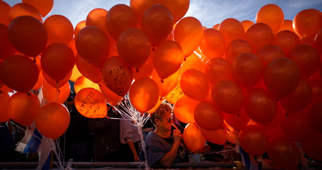 Manifestantes sostienen globos naranjas durante un acto en solidaridad con Kfir Bibas, un bebé israelí que pasó su primer cumpleaños retenido por Hamás en Gaza, en Tel Aviv, Israel, el 18 de enero de 2024.