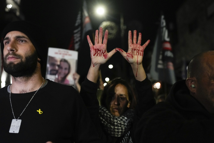 Familiares y partidarios de los rehenes israelíes retenidos por Hamás en Gaza participan en una protesta para exigir su liberación, en el exterior del Knesset, el parlamento israelí, en Jerusalén, el 22 de enero de 2024. La frase escrita con sangre falsa en las manos de la mujer dice "El tiempo se acaba", en hebreo.