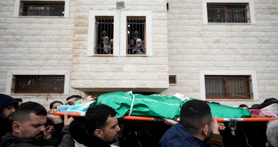 Dolientes palestinos cargan el cuerpo de Muhammad Jalamneh, envuelto en la bandera del grupo armado Hamás, durante su funeral tras ser asesinado en un asalto a hospital Ibn Sina en la localidad cisjordana de Yenín, el martes 30 de enero de 2024. Foto: Majdi Mohammed, AP