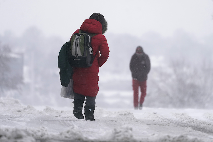 La gente camina sobre una calle nevada durante la tormenta invernal que azota a la región en Kansas City, Misuri, EU, el martes 9 de enero del 2024.