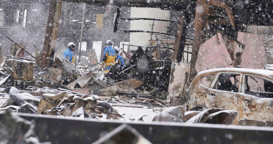 La nieve cae mientras la policía continúa una operación de búsqueda en torno a un mercado quemado en Wajima, en la prefectura japonesa de Ishikawa, el domingo 7 de enero de 2024. Un gran sismo golpeó Japón el lunes 1 de enero, mató a decenas de personas, derribó edificios y provocó aludes de tierra.