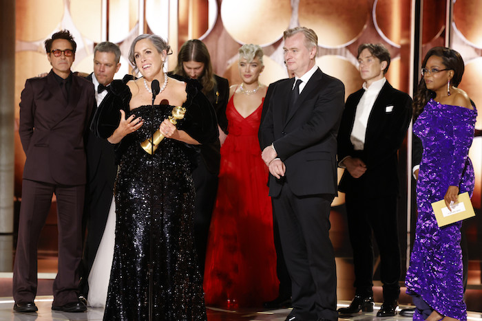 En esta imagen proporcionada por CBS, la productora Emma Thomas, frente a la izquierda, recibe el premio a Mejor Película Dramática por "Oppenheimer" acompañada por miembros del elenco y el equipo de producción incluyendo a Robert Downey Jr., de izquierda a derecha, Matt Damon, Ludwig Göransson, Florence Pugh, el director Christopher Nolan, Cillian Murphy, mientras los ve la presentadora de la gala Oprah Winfrey en la 81a edición de los Globos de Oro el domingo 7 de enero de 2024, en el Hotel Beverly Hilton en Beverly Hills, California.