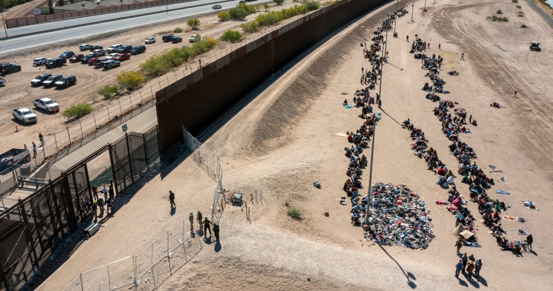 Migrantes forman filas frente a la valla en la frontera de Estados Unidos con México a la espera de ser transportados a una instalación de la Patrulla Fronteriza, el 10 de mayo de 2023, en El Paso, Texas.