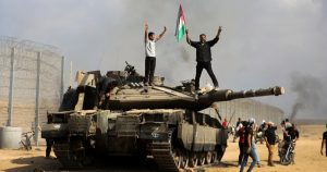 Palestinos ondean una bandera nacional y celebran sobre un tanque israelí destruido más allá de la cerca fronteriza en el sur de la Franja de Gaza, al este de Jan Yunis, el 7 de octubre de 2023.