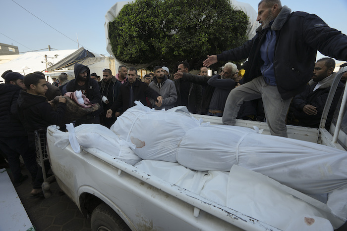 Palestinos suben los cuerpos de sus familiares que murieron en un bombardeo israelí contra la Franja de Gaza a una camioneta en la ciudad de Deir al Balah, Franja de Gaza, el martes 2 de enero de 2024.