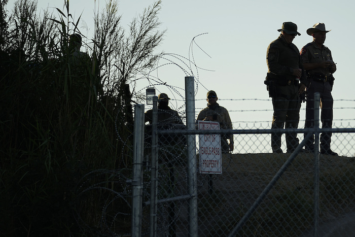 Policías estatales de Texas vigilan junto a un letrero de "Prohibido el paso" y alambre de púas a lo largo de las márgenes del Río Bravo (o Grande), el 1 de agosto de 2023, en Shelby Park, Eagle Pass, Texas.