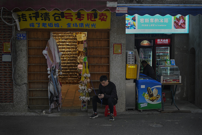 Un vendedor descansa afuera de su tienda de souvenirs en Xiamen, en el sureste de China, el 27 de diciembre de 2023.