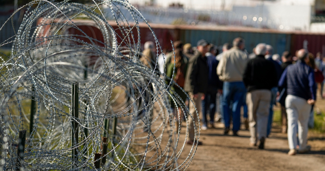 Una cerca de alambre de púas se erige a un costado de un camino de tierra por el que avanzan legisladores cerca de la frontera entre Texas y México, el 3 de enero de 2024, en Eagle Pass, Texas.