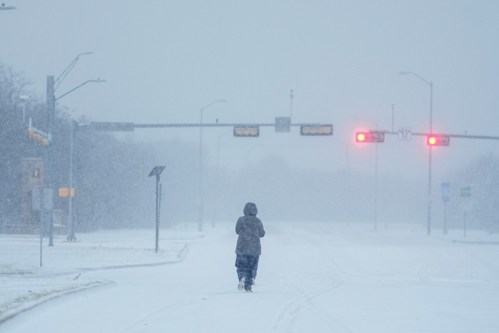 Una persona corre en una avenida cubierta de nueve durante una tormenta invernal, el lunes 15 de enero de 2024, en Grand Prairie, Texas.