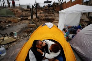 Franchesca Mori limpia la cara de su pareja Miguel Alcaino después de acampar para pasar la noche en el lugar donde estaba su casa antes de ser destruida por un incendio forestal en el barrio Villa Independencia de Viña del Mar, Chile, el martes 6 de febrero de 2024.