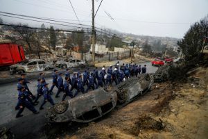 Personal de la Armada de Chile pasa junto a autos volcados y carbonizados mientras se despliegan para ayudar al vecindario de Villa Independencia afectado por incendios forestales en Viña del Mar, Chile, el martes 6 de febrero de 2024. 