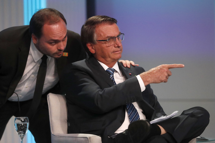 Carlos Bolsonaro, hijo del expresidente brasileño Jair Bolsonaro, susurra al oído a su padre en su llegada al debate presidencial en Río de Janeiro, Brasil, el 29 de septiembre de 2022.