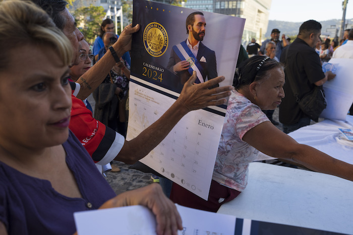 Gente recibe calendarios con la imagen del Presidente de El Salvador, Nayib Bukele, en un acto de su campaña de reelección en San Salvador, El Salvador, el miércoles 31 de enero de 2024. 