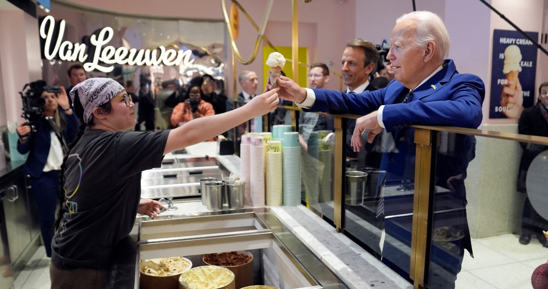 El Presidente Joe Biden recibe un helado en la heladería Van Leeuwen Ice Cream, el lunes 26 de febrero de 2024, en Nueva York. Detrás de él se encuentra el presentador televisivo Seth Meyers.