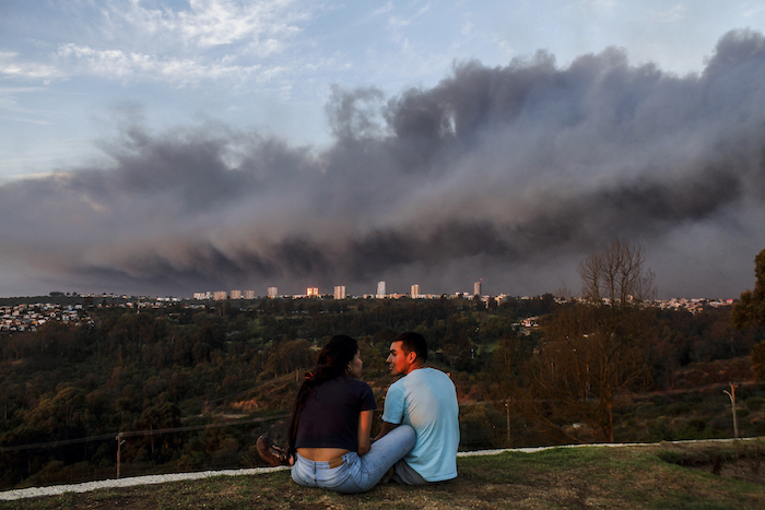 Una pareja charla en un parque mientras el humo causado por los incendios cubre el cielo, en Viña Del Mar, Chile, el 2 de febrero de 2024.