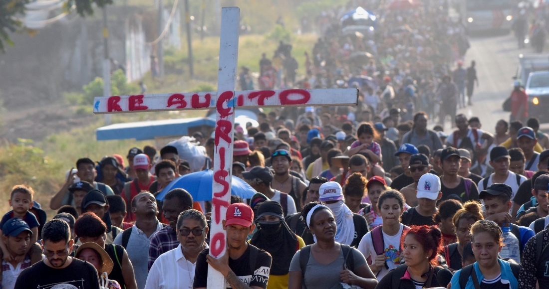 Migrantes que caminan por la carretera llevan una cruz que dice en español "Cristo Resucitado" durante la Semana Santa mientras avanzan por Tapachula en el estado mexicano de Chiapas, el lunes 25 de marzo de 2024.