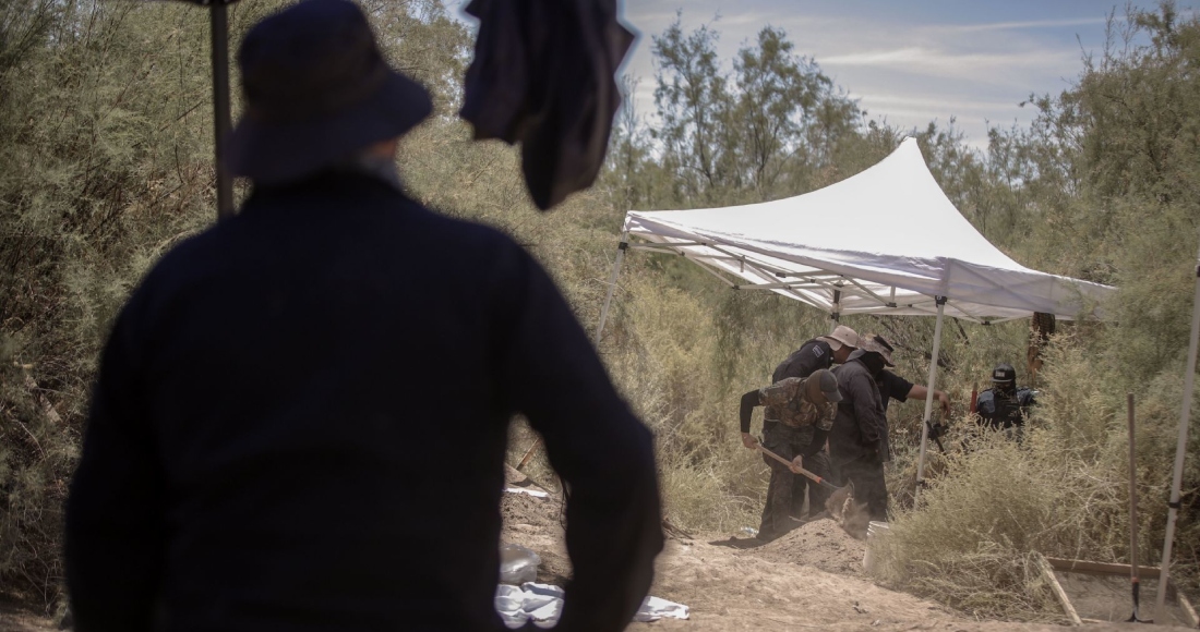 Un agente de la fiscalía observa como sus compañeros trabajan sobre un cuerpo enterrado, hallado en la fosa clandestina encontrada en la colonia Miguel Alemán en el Valle de Mexicali.