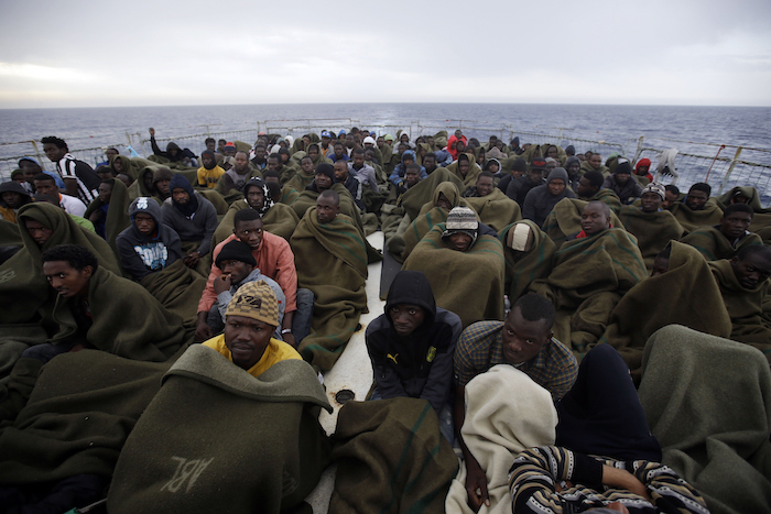 Migrantes sentados en la cubierta del barco de la Marina belga Godetia después de ser rescatados en el mar durante una misión de búsqueda y rescate en el Mediterráneo cerca de la costa libia, el 24 de junio de 2015.