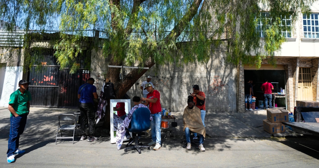 Migrantes venezolanos se cortan el pelo junto a las vías del tren bordeadas por tiendas de campaña improvisadas en la Ciudad de México, el martes 26 de marzo de 2024.