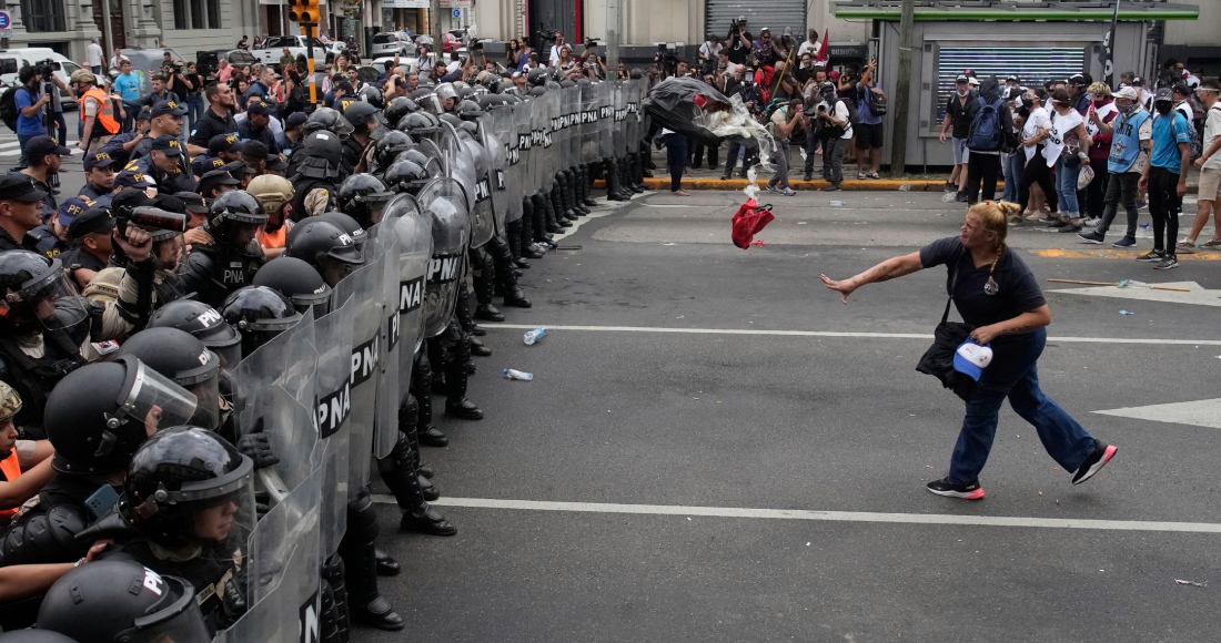 Una mujer arroja una bolsa de basura a la policía que bloquea una manifestación contra la escasez de alimentos en los comedores populares y las reformas económicas propuestas por el presidente Javier Milei en Buenos Aires, Argentina, el lunes 18 de marzo de 2024.