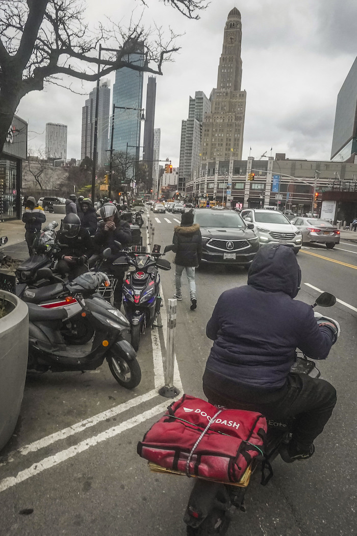 Repartidores de comida se reúnen para recibir pedidos ante restaurantes de comida rápida en la avenida Flatbush de Brooklyn, el lunes 29 de enero de 2024, en Nueva York.