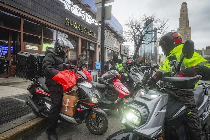 Repartidores de comida se reúnen para recibir pedidos en restaurantes de comida rápida en la avenida Flatbush de Brooklyn, el lunes 29 de enero de 2024, en Nueva York.