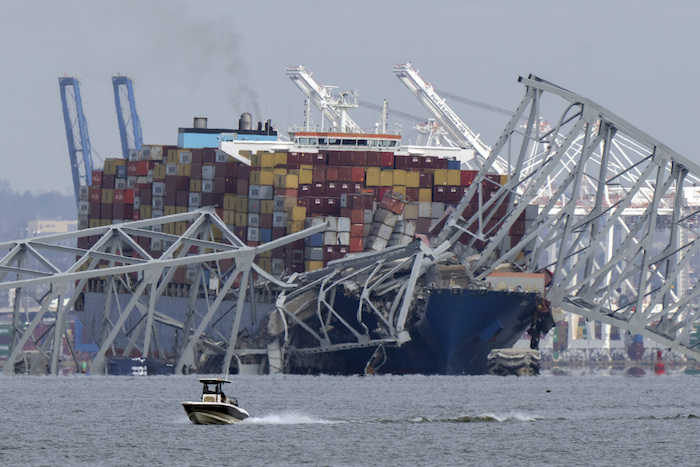 Un barco pasa frente a un buque portacontenedores que chocó contra el puente Francis Scott Key, el martes 26 de marzo de 2024, en Baltimore, Maryland.