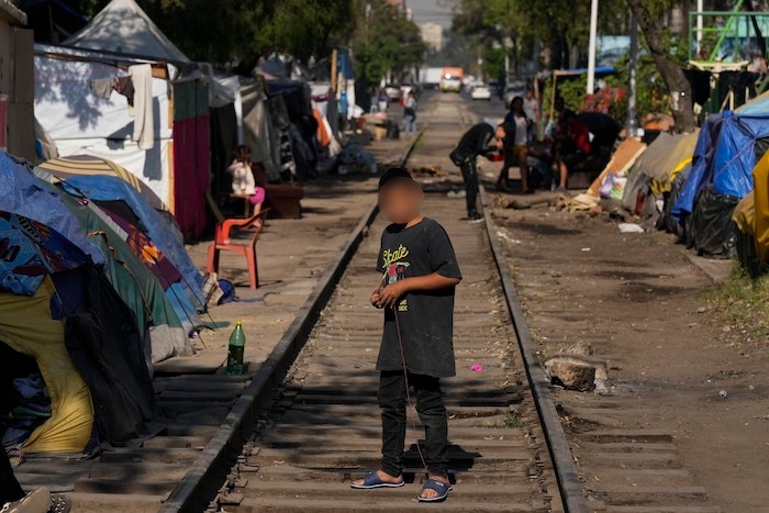 Un joven migrante venezolano juega con una peonza en las vías del tren bordeadas de tiendas de campaña y refugios improvisados en la Ciudad de México, el martes 26 de marzo de 2024.