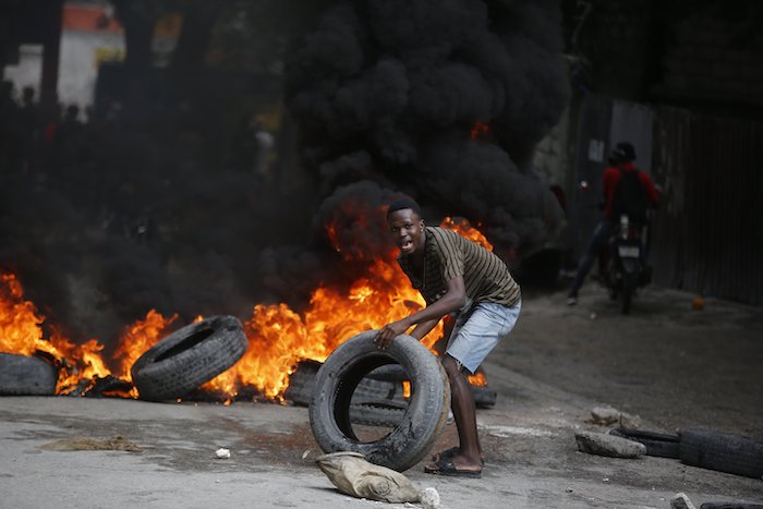 Un manifestante coloca neumáticos en una barricada en llamas durante una protesta para exigir la renuncia del Primer Ministro, Ariel Henry, en Puerto Príncipe, Haití, el 7 de febrero de 2024.