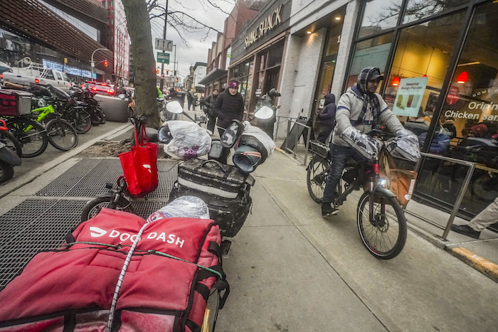 Un repartidor de comida sale tras recoger un pedido de un restaurante de comida rápida en la avenida Flatbush de Brooklyn, el lunes 29 de enero de 2024, en Nueva York.