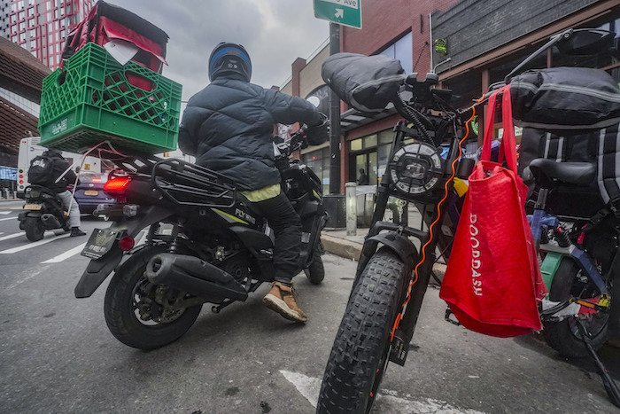 Un repartidor de comida sale tras recoger un pedido en un restaurante de comida rápida en la avenida Flatbush de Brooklyn, el lunes 29 de enero de 2024, en Nueva York.