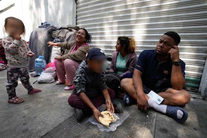 Una familia de migrantes venezolanos desayuna junto a las vías del tren en la Ciudad de México, el martes 26 de marzo de 2024.