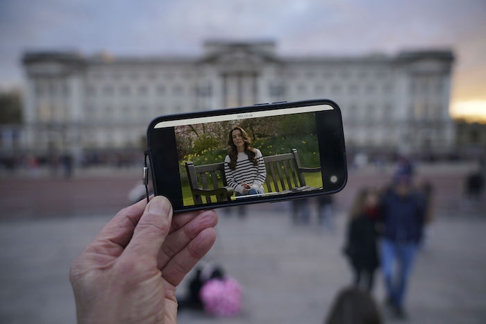 Una persona mira un anuncio de la princesa de Gales en un celular fuera del Palacio de Buckingham, el viernes 22 de marzo de 2024. 