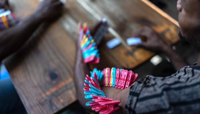 Un jugador de dominó con pinzas en el brazo colocadas cada vez que pierde en una escuela pública que sirve de refugio a personas desplazadas de sus hogares por los enfrentamientos entre pandillas en Puerto Príncipe, Haití, el lunes 22 de abril de 2024.