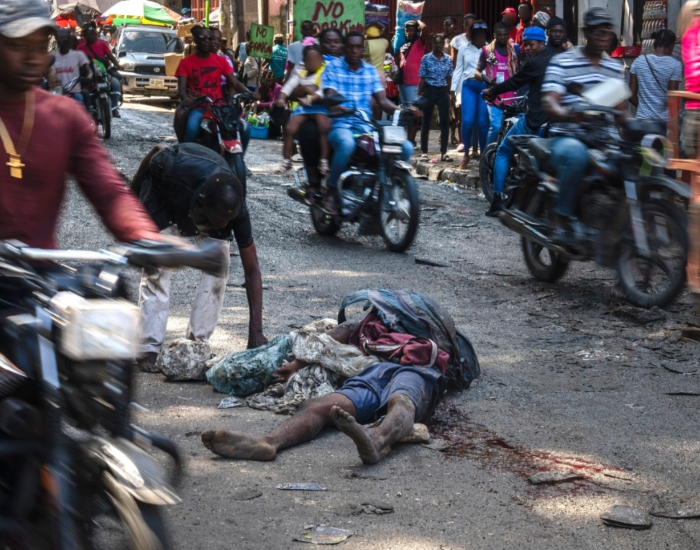 Un cuerpo tirado en medio de la calle mientras la gente pasa a su alrededor en el vecindario de Petion-Ville, Puerto Príncipe, Haití, el lunes 22 de abril de 2024.