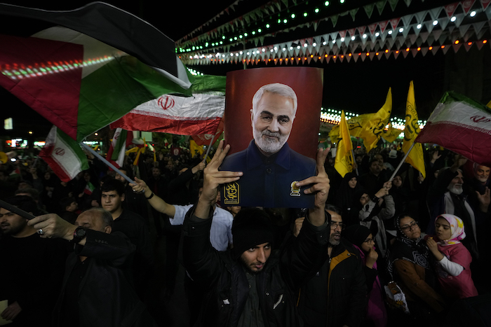 Manifestantes ondean banderas iraníes y palestinas mientras uno de ellos sostiene un cartel con la imagen del fallecido General de la Guardia Revolucionaria iraní Qassem Soleimani, asesinado en un ataque estadounidense en 2020, durante una manifestación contra Israel para condenar la muerte de miembros de la Guardia Revolucionaria en Siria, en la plaza Felestin (Palestina) de Teherán, Irán, el lunes 1 de abril de 2024.