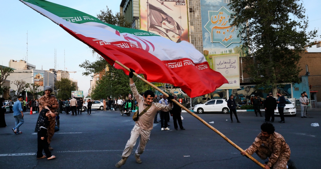 Manifestantes ondean una enorme bandera iraní en su reunión antiisraelí frente a la plaza Felestin (Palestina), en Teherán, Irán, el lunes 15 de abril de 2024.