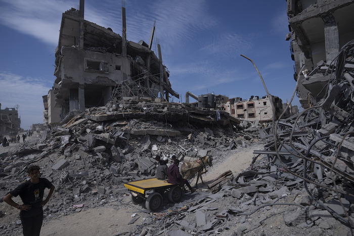 Palestinos caminan entre la destrucción tras una ofensiva aérea y terrestre israelí en Jan Yunis, sur de la Franja de Gaza, el lunes 8 de abril de 2024.