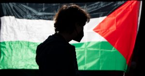 La silueta de un alumno de la Universidad de Oregon se ve ante una bandera palestina en un campamento de carpas levantado en la universidad como protesta por la guerra entre Hamás e Israel, el 29 de abril de 2024 en Eugene, Oregon.