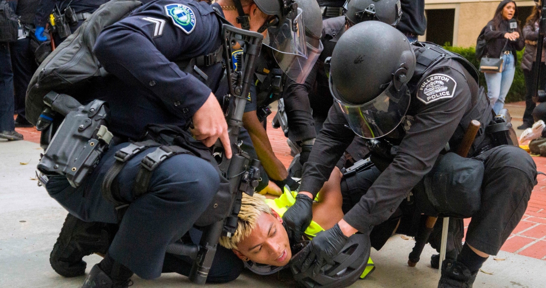 La policía tira al suelo a un manifestante pro-palestino para atarle las muñecas en la Universidad de California, Irvine, después de que la policía comenzara a desplazar a los manifestantes y un campamento fuera del patio, el 15 de mayo de 2024, en Irvine, California.