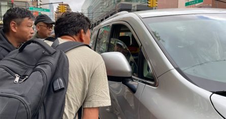 Wang Gang, de 36 años, delante, un migrante chino, habla con el conductor de un coche junto a otras personas mientras intentan conseguir un trabajo jornalero en la construcción o en otro oficio en el barrio de Flushing, en el barrio neoyorquino de Queens, el 3 de mayo de 2024.