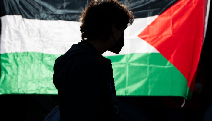 La silueta de un alumno de la Universidad de Oregon se ve ante una bandera palestina en un campamento de carpas levantado en la universidad como protesta por la guerra entre Hamás e Israel, el 29 de abril de 2024 en Eugene, Oregon.