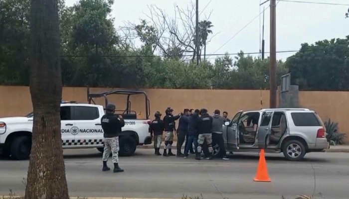 En esta imagen tomada de un video, fuerzas de seguridad mexicanas registran a hombres en un puesto de control, el jueves 2 de mayo de 2024, en Ensenada, México.