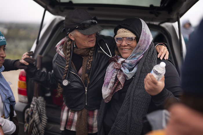 Julia Paredes, a la derecha, de Perú, recibe un abrazo de una voluntaria, Karen Parker, tras cruzar la cercana frontera con México el jueves 25 de abril de 2024, en Boulevard, California.